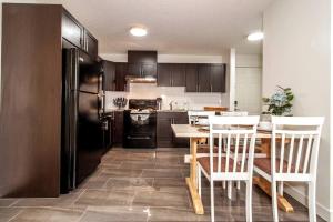 a kitchen with a table and a black refrigerator at Beach Vibes - KING Bed - Fireplace - Garage - WiFi in Edmonton