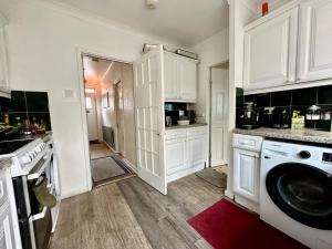 a kitchen with white cabinets and a washer at Whitechapel Rooms R1 in London