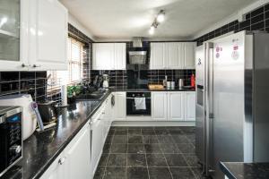 a kitchen with white cabinets and black tile floors at Orchard House: 4 Bed/3 Bath in Thamesmead in London