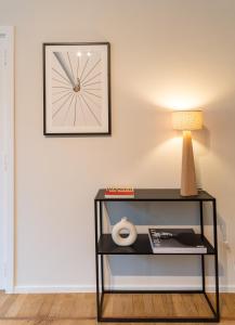 a table with a lamp and a clock on a wall at Magnifique appartement - Quartier Louise! in Brussels