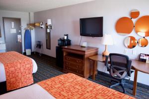 Habitación de hotel con cama, escritorio y TV. en Howard Johnson by Wyndham Lexington, en Lexington