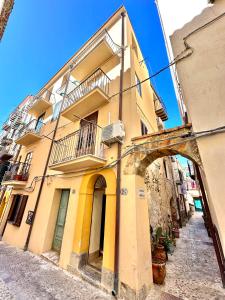ein gelbes Gebäude mit einem Bogen in einer Straße in der Unterkunft Casa Marzia by Housilia in Cefalú