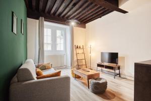 ein Wohnzimmer mit einem Sofa und einem TV in der Unterkunft L'authentique Bressan in Bourg-en-Bresse