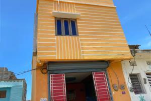 a yellow building with red shutters on it at GRG M S M Residency Puri in Puri