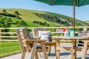 a wooden table and chairs with an umbrella at Waun Yscir Rural escape in the Brecon Beacons in Brecon