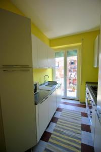 ローマにあるCASA UMBERTOの黄色の壁と白いキャビネット、シンク付きのキッチン