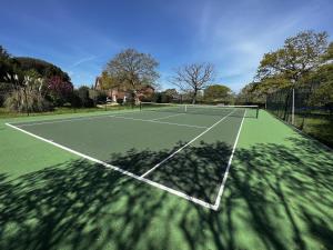 a tennis court with a shadow on the court at The Cottage, Shalfleet House in Shalfleet