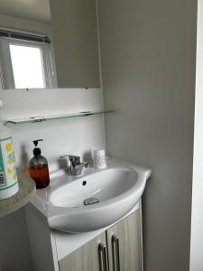 a bathroom with a white sink and a mirror at Mobilhome clim La Falaise 4 étoiles in Narbonne