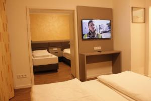 um quarto com uma televisão e um quarto com duas camas em Isar City Hotel em Munique