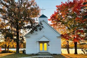 una pequeña iglesia blanca con puertas amarillas y árboles en Walleye Cabin Spitzer Lakefront Minnesota, en Clitherall