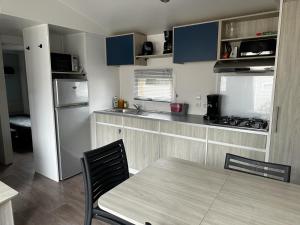 a kitchen with a table and a kitchen with blue cabinets at Mobilhome clim La Falaise 4 étoiles in Narbonne