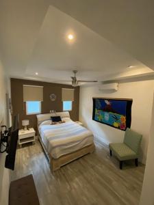 een slaapkamer met een groot bed en een stoel bij Playa Potrero - modern 3 BR home centrally located - Casa Coastal Serenity in Guanacaste