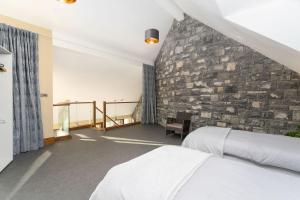 a bedroom with two beds and a stone wall at Property 434 - Oughterard in Oughterard