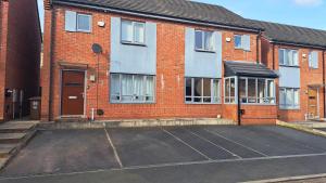 an empty parking lot in front of a brick building at Tropical Sun Homes - Beautiful spacious 3 bed home in a serene environment with free parking for 2 cars in Manchester