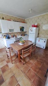 a kitchen with a wooden table and chairs and a kitchen with white appliances at Casa Pé na Areia Cantão do Bora Bora - Manaaki Surf Hostel in São Sebastião