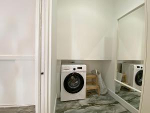 eine Waschmaschine in einer Waschküche mit Spiegel in der Unterkunft Estudio Wellness Casa Abi in San Sebastián de los Reyes