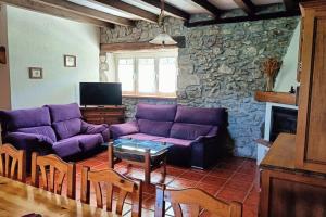 a living room with purple couches and a stone wall at Casona Pico Candiano in San Miguel de Aras