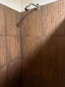 a shower with wooden walls and a shower head at Patio Hangar Toluca Aeropuerto (antes BoxPark) in Toluca