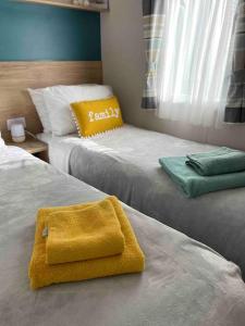 two beds with a yellow towel sitting on top of them at Hoburne Devon Bay - Hot Tub 2 Bed Paignton in Paignton