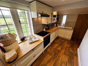 a kitchen with white cabinets and wooden floors and windows at The Old Abbey Farmhouse - Pet Friendly in Ryde