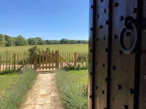 uma porta de madeira com um portão num campo em The Old Abbey Farmhouse - Pet Friendly em Ryde