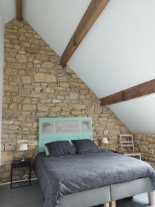 uma cama num quarto com uma parede de pedra em Nouzet gites et lits em Eyzerac