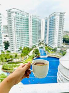 eine Person, die eine Tasse Kaffee vor einer Stadt hält in der Unterkunft Staycation in the Corner by MJJ in Manila