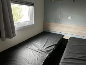 a bedroom with a bed and a window at Mobilhome clim La Falaise 4 étoiles in Narbonne