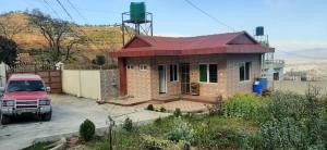 uma casa com um camião vermelho estacionado em frente dela em Small house in boshan kathmandu em Dakshīnkāli