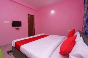 Hotel Madison Patia Inn Bhubaneswar في بوهفانيشفار: غرفة نوم وردية مع سرير كبير مع وسائد حمراء