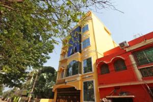 Hotel Madison Patia Inn Bhubaneswar في بوهفانيشفار: مبنى أصفر وأحمر مع نوافذ زرقاء