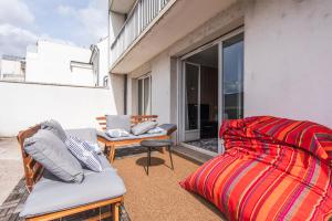 a patio with a couch and chairs on a balcony at Appartement grande terrasse proche de Tours centre in Tours
