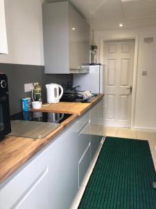 a kitchen with white cabinets and a green rug at Self catering private annex near Ferndown in Ferndown