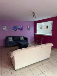 ein Wohnzimmer mit einem Sofa und einer lila Wand in der Unterkunft Habitación privada en casa compartida. in Tepic