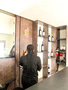 una mujer sentada en un mostrador mirando botellas de vino en BiggysPlace en Ijebu Ode