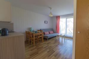 eine Küche und ein Wohnzimmer mit einem Tisch und einem Sofa in der Unterkunft Bursztyn II Domki Apartamenty Pokoje w Sarbinowie blisko morza in Sarbinowo