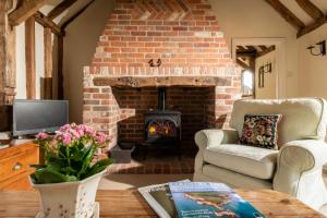 a living room with a brick fireplace with two chairs and a table at Byre in Herstmonceux
