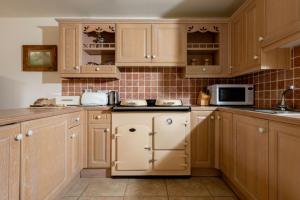 a kitchen with wooden cabinets and a refrigerator at Byre in Herstmonceux