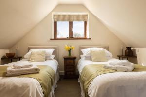 a attic room with two beds and a window at Byre in Herstmonceux