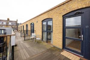 ein Backsteingebäude mit einer Terrasse mit einem Tisch darauf in der Unterkunft The Tooting Hideout - Dazzling 3BDR Flat with Balcony in London