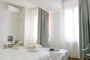 una camera d'albergo con due letti con lenzuola bianche di Casa Alidosi a Imola