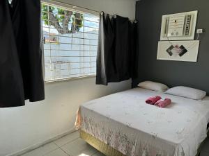 a bedroom with a bed with two pink slippers on it at Casa da Esquina Pousada in Recife