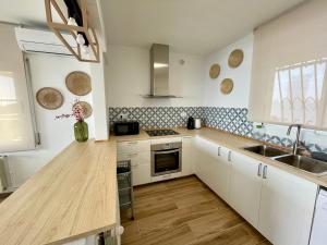 a kitchen with white cabinets and a wooden counter top at SeaHomes Vacations, LA CASA BLUE Mediterranean Lifestyle in Blanes