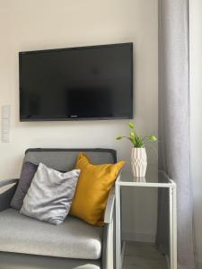 ein Wohnzimmer mit einem Sofa und einem TV an der Wand in der Unterkunft Apartament CARPANO, Ogrodnicza 7 / KARPACZ in Karpacz