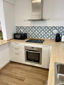a kitchen with white cabinets and a stove top oven at SeaHomes Vacations, LA CASA BLUE Mediterranean Lifestyle in Blanes