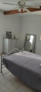 Schlafzimmer mit einem Bett, einer Kommode und einem Deckenventilator in der Unterkunft Les garrigues in Pernes-les-Fontaines