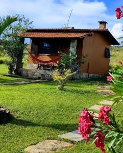 uma pequena casa num quintal com flores em Pousada Ceu e Serra em Carrancas