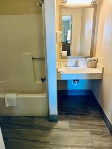 a bathroom with a sink and a tub and a mirror at Days Inn by Wyndham Fort Wayne in Fort Wayne