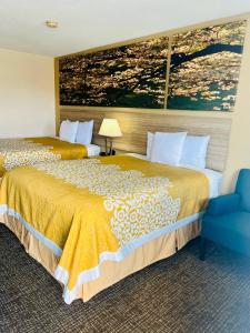 una habitación de hotel con 2 camas y una silla azul en Days Inn by Wyndham Fort Wayne, en Fort Wayne