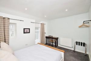 a white bedroom with a bed and a desk at Modern Cottage 3 Bed Family Walking & Cycling in Cefn-coed-y-cymmer